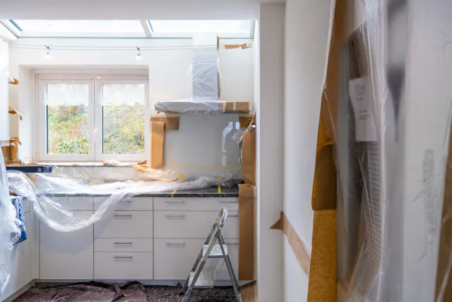 Cocina en plena reforma con los muebles protegidos con plástico y papel